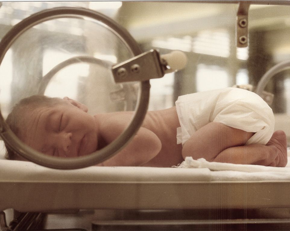 Mała dłoń wcześniaka z plasterkiem, zaciskająca się na palcu dorosłego – symbol walki o życie, którą wspiera Twoje 1,5% podatku.