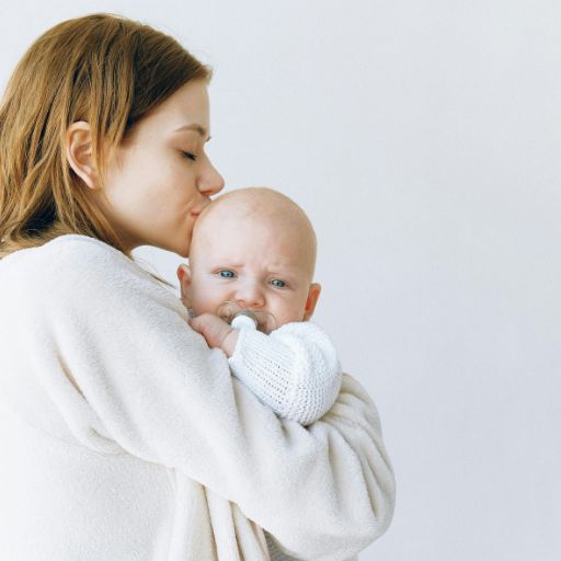 Mama trzymająca w objęciach dziecko na białym tle